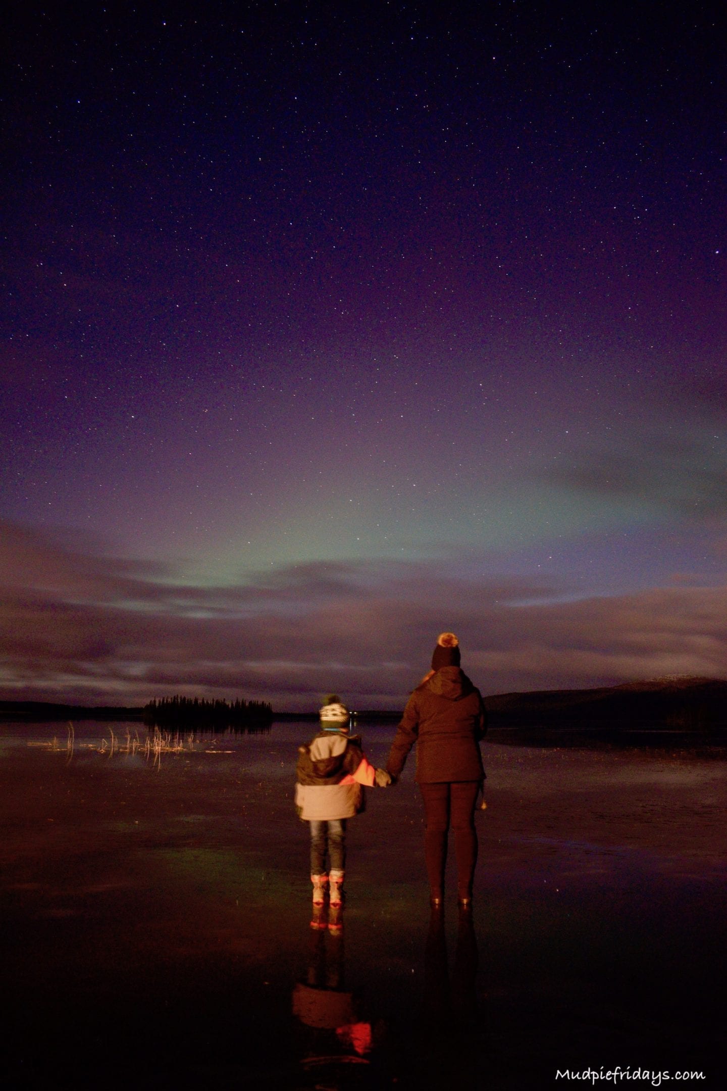 Charlie and I standing on a frozen lake with the aurora above us