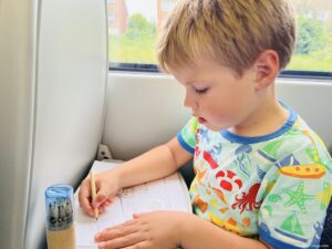 Harry with some colouring sheets on the train