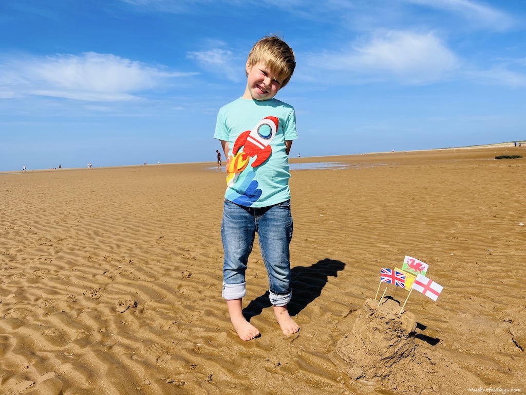 building a sand castle with paper flags at the UK seaside