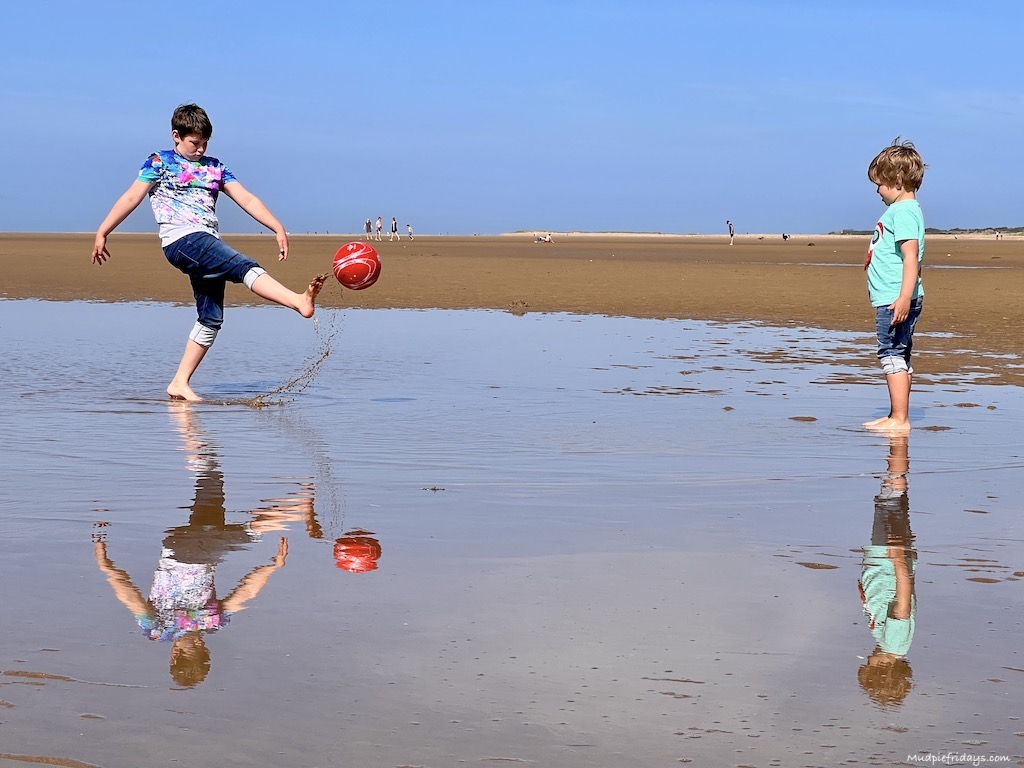 playing football on hunstanton beach golden sands and shallow waters giving reflection of the ball - north norfolk coast