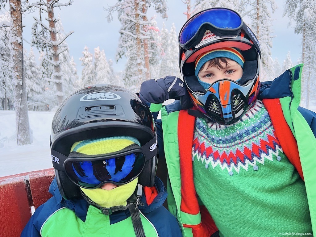The boys in their helmets waiting to try out some snowmobiles for the first time