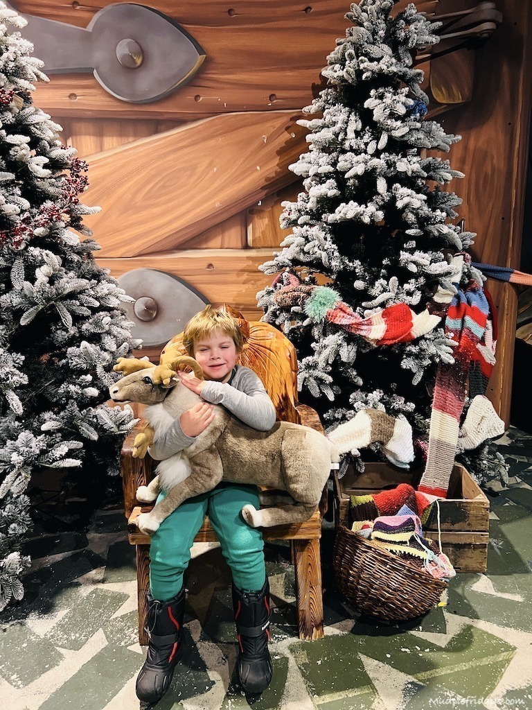Harry cuddling a soft toy reindeer in front of two christmas trees