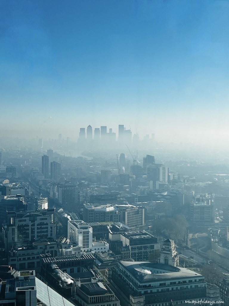 Canary Wharf and surrounding building in the misty morning with clouds around the buildings and blue skies