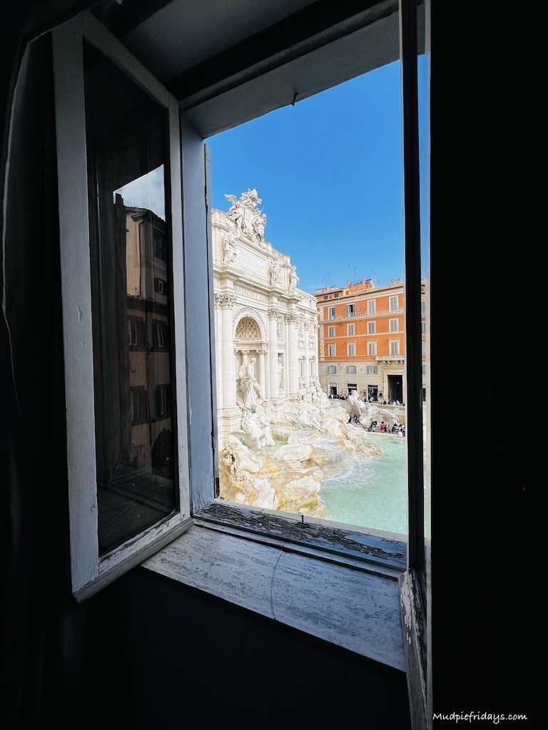 A picture of the Trevi fountain taken with the window still in the picture to show distance if looking for apartments near the Trevi fountain in Rome