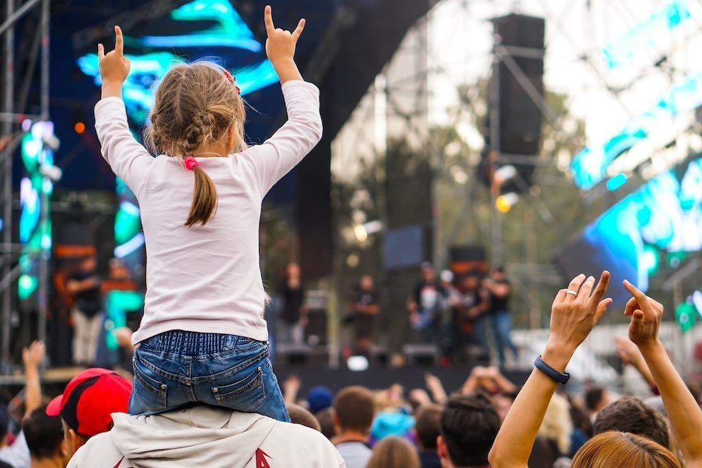 Little girl on parents shoulders at a music kids festival UK