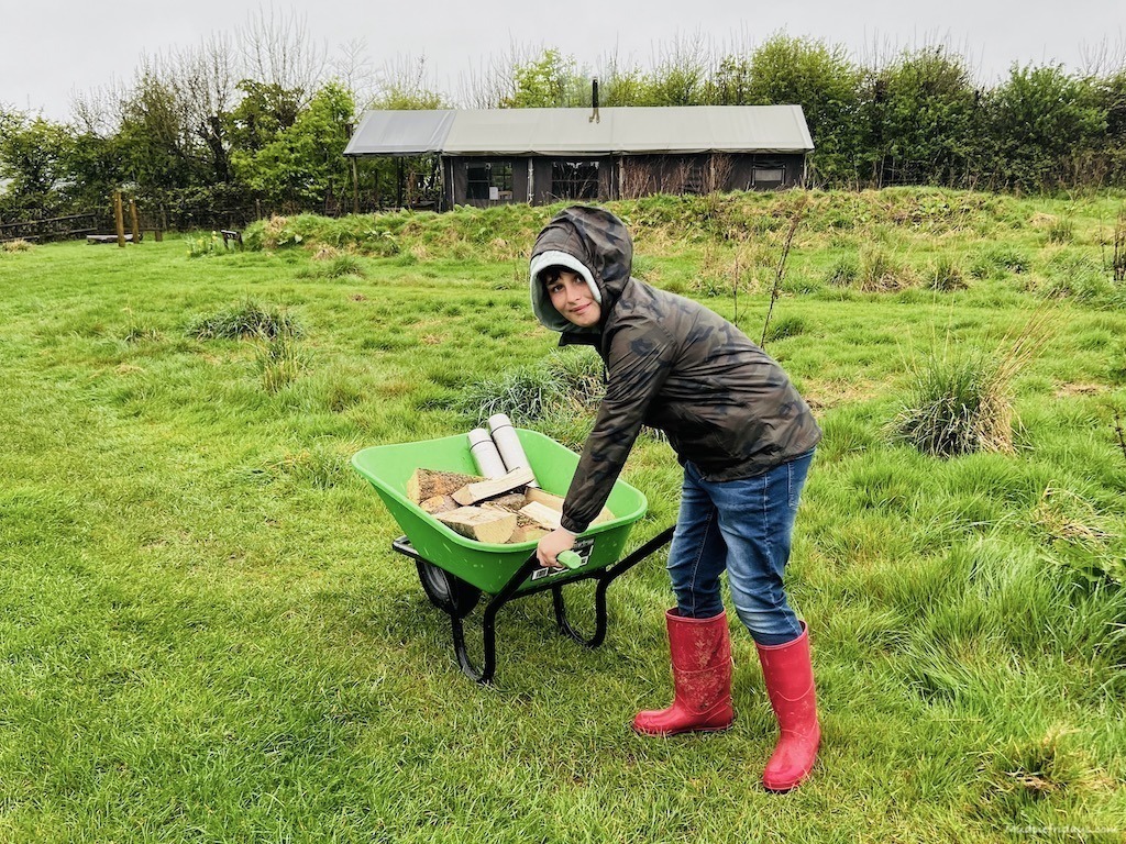 Charlie collecting wood to take back to our safari tent while glamping in Somerset with feather down farm stays