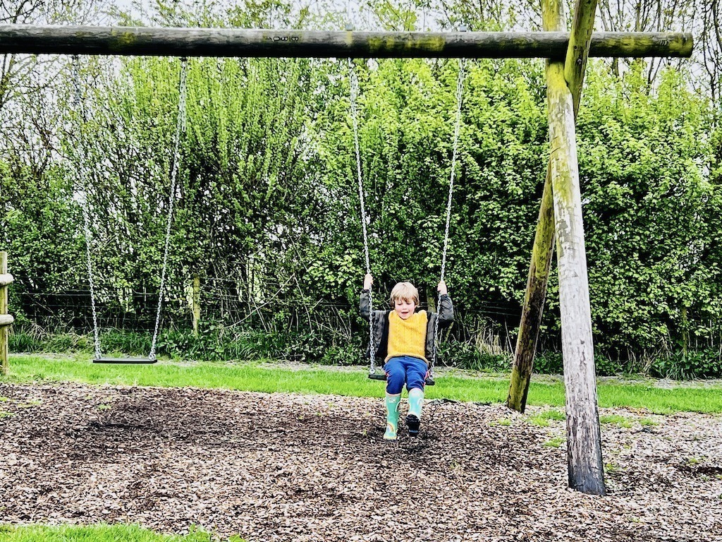 Harry on the swings in a yellow jumper