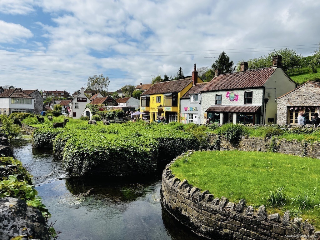 Cheddar Village high street in mutli coloured cottages with a river in front