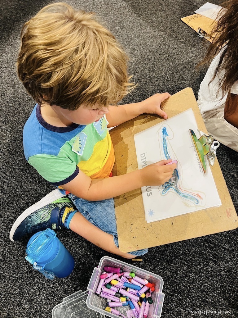 Harry tracing a dinosaur at the natural history museum using tracing paper and bright crayons