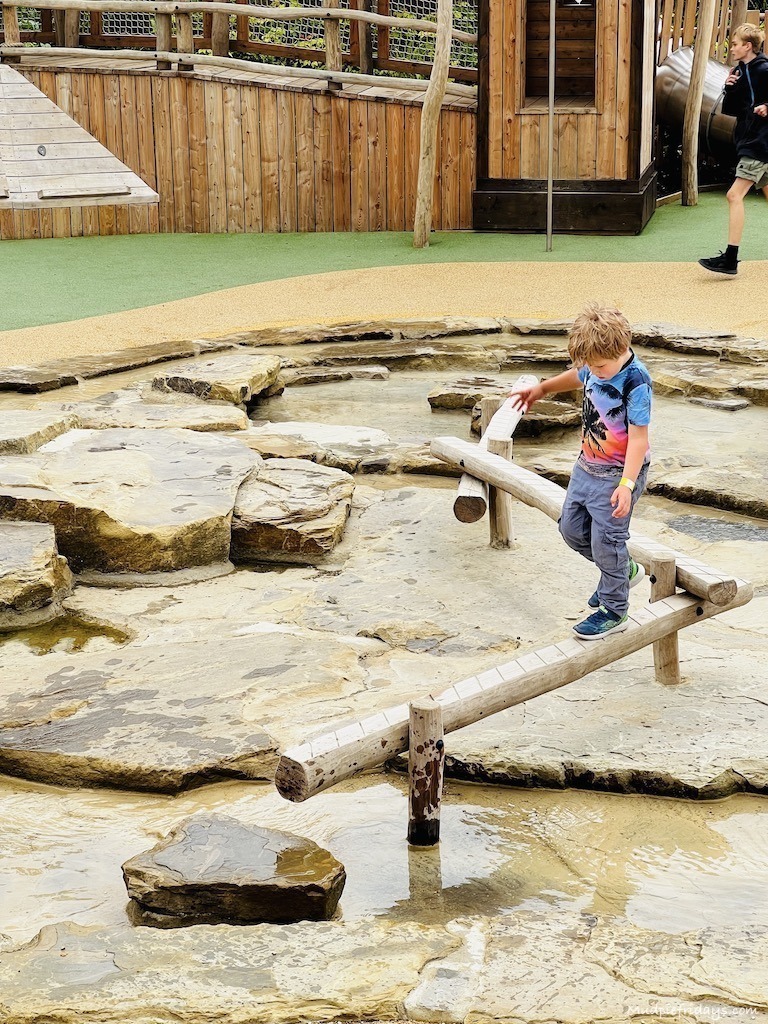 Harry balancing on a beam over water in the adventure play area - things to do at Blenheim Palace
