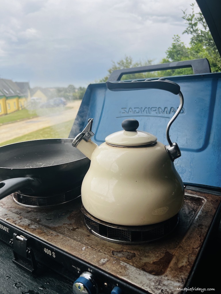 Old fashioned metal cream teapot on a gas camping hob