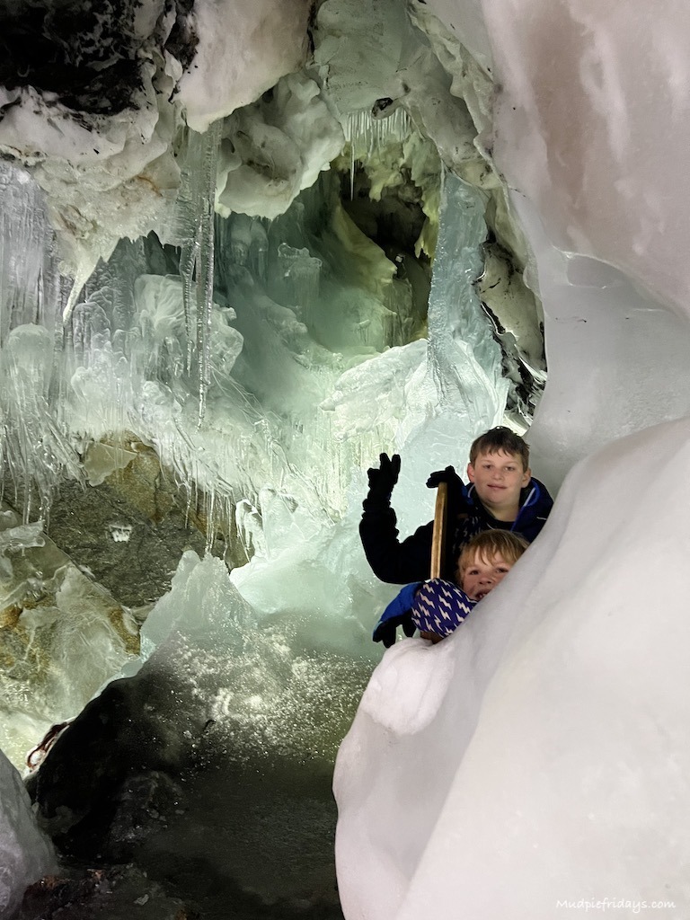 The boys in the ice cave at the top of the hintertux glacier with ice formations behind them