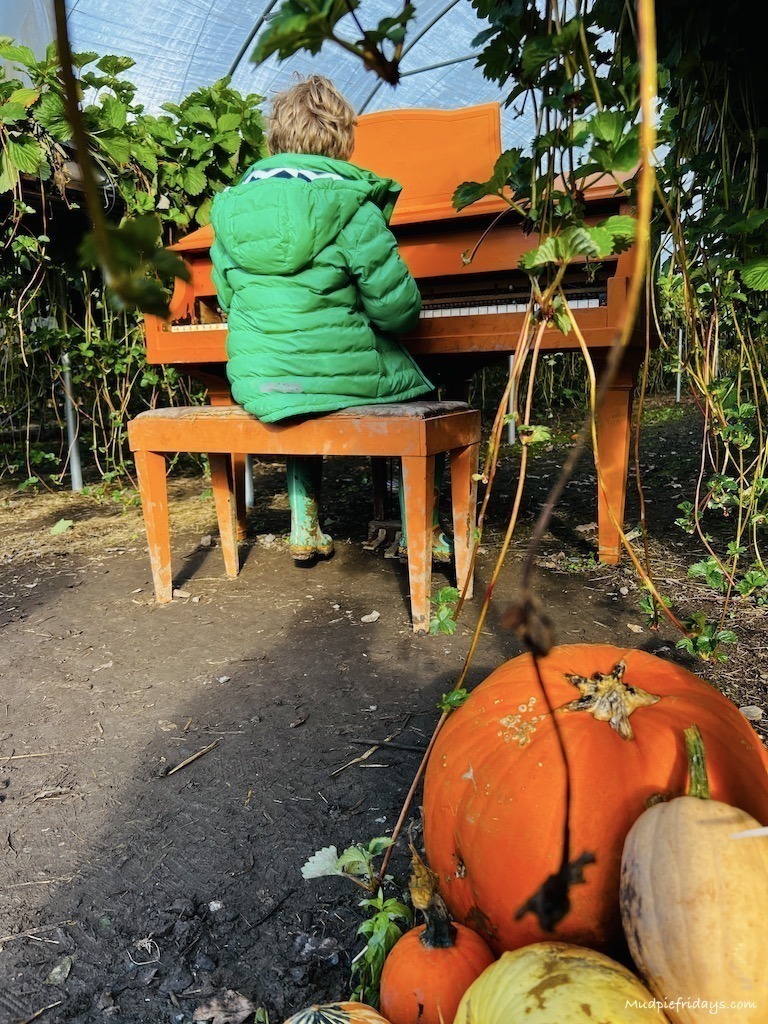 Harry sitting and paying a bright orange piano