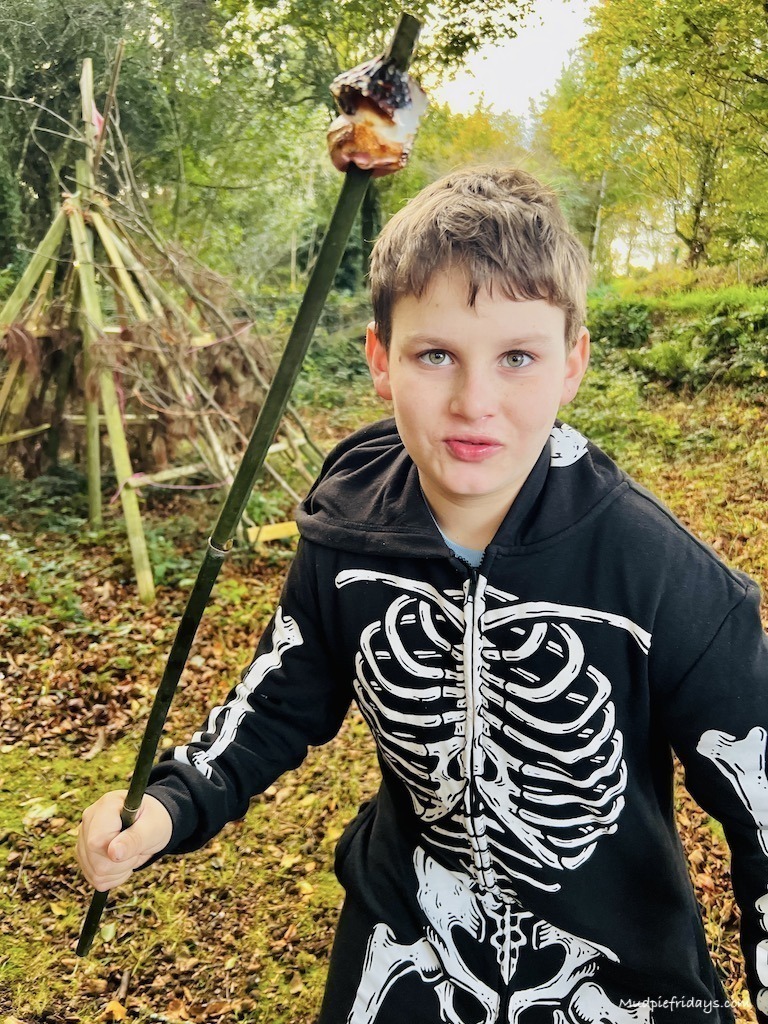 Charlie in his skeleton outfit with a toasted marshmallow on a stick