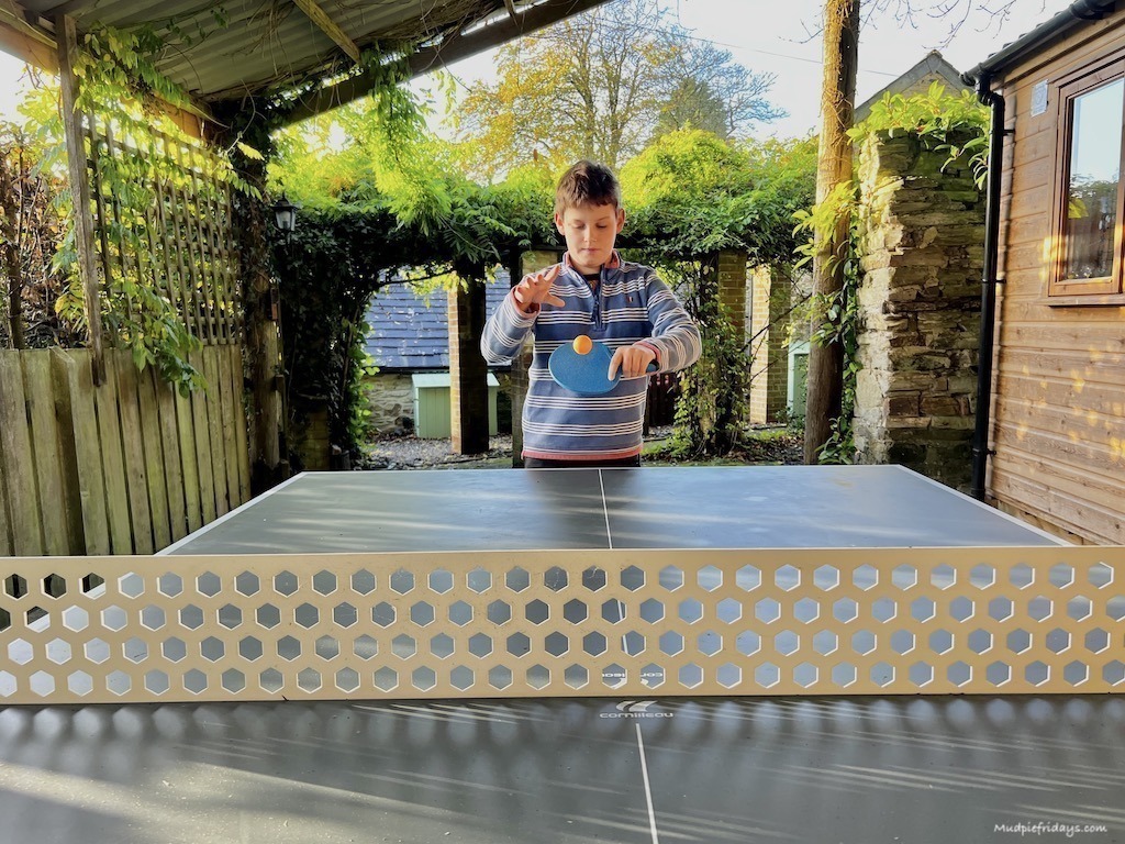 Charlie playing table tennis with a paddle and orange ping pong ball