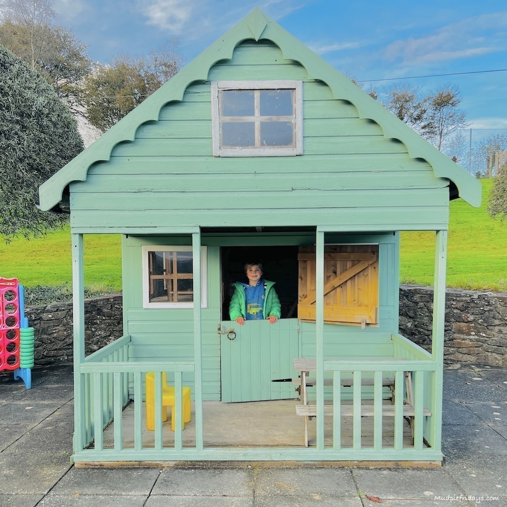 Harry in a large painted wendy house in the garden at our farm stay in Cornwall