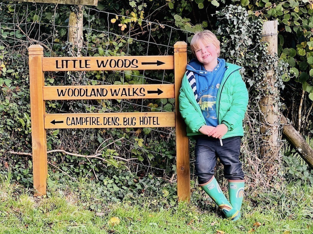 Harry standing next to the woods this way sign at Glynn Barton Cottages