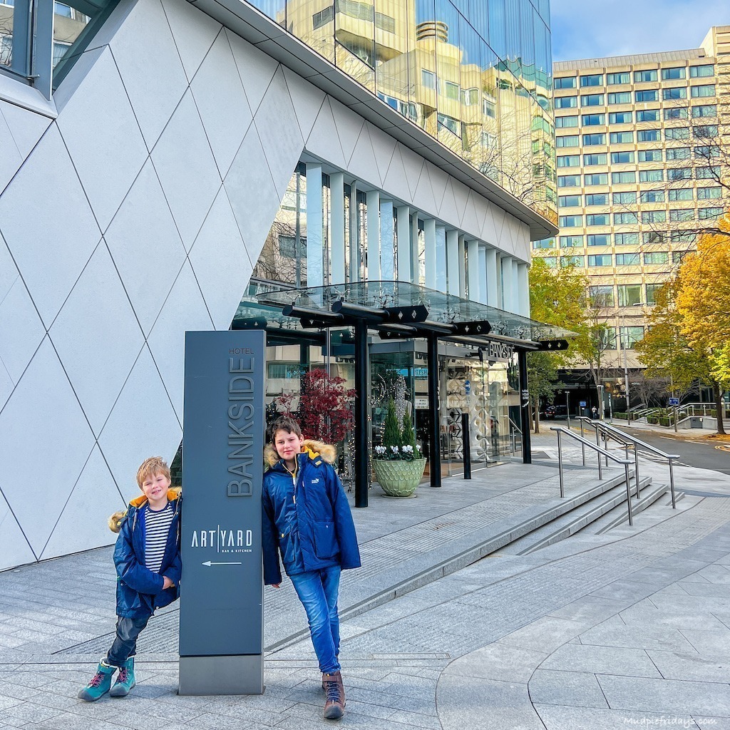 The boys standing outside the hotel next to the art yard bar and restaurant sign