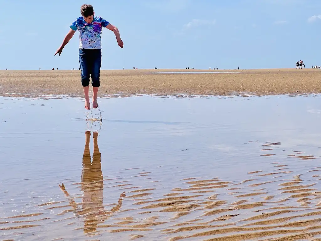Charlie on Hunstanton beach jumping and the reflection in the water