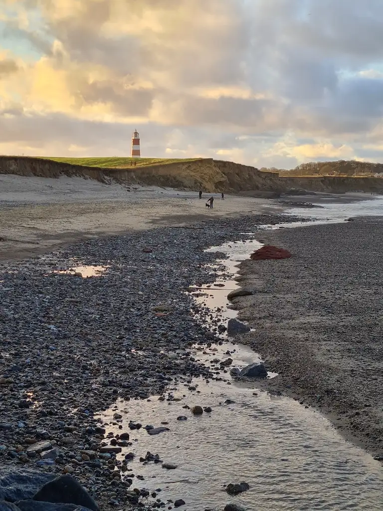 Happisburgh lighthouse in the distance at sunset