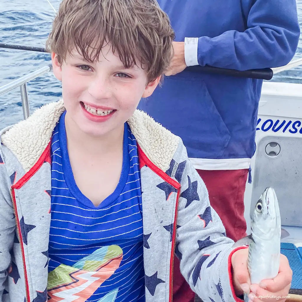 Charlie holding a mackerel which he caught as sea with a big smile on his face