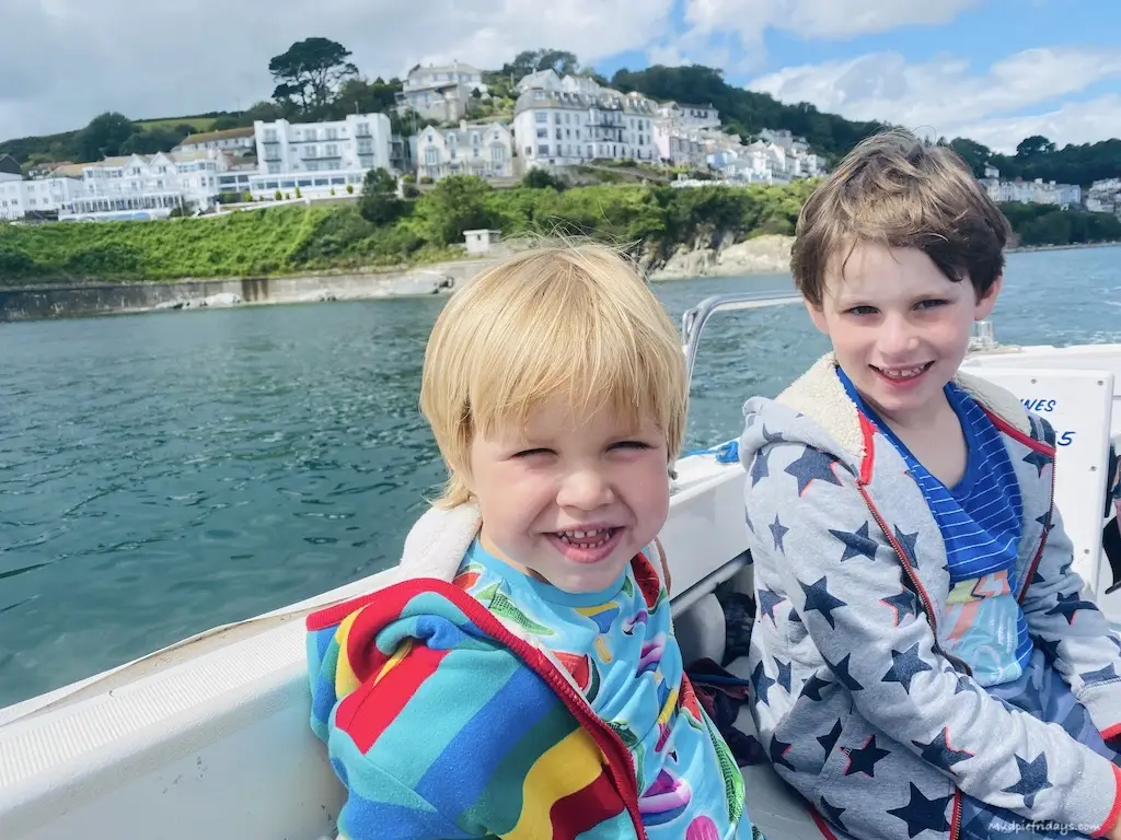 The boys sitting in a boat with Looe in the background during our boat trip