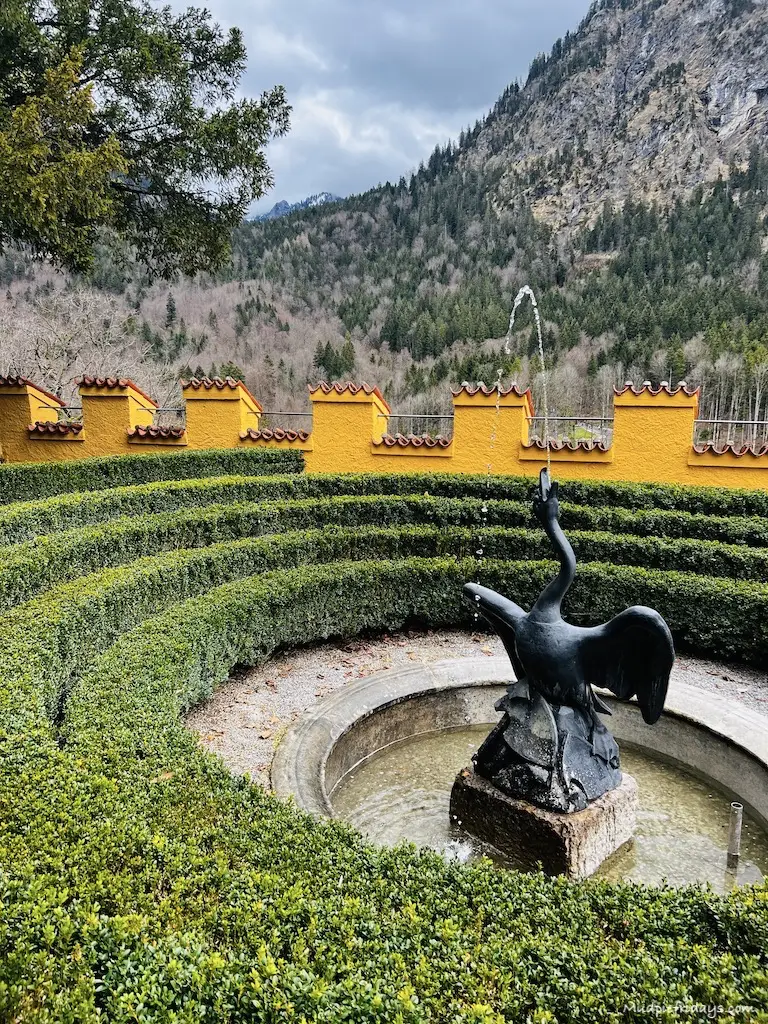 One of the fountains in the gardens, surrounded by box hedging and yellow walls in the background