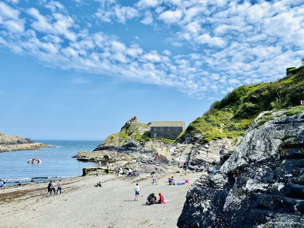 Polperro beach in the summer with blue skies and grey single and sand beach