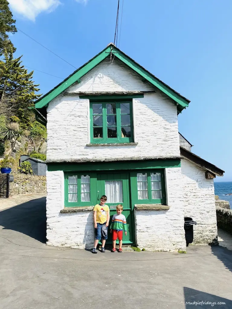 Boys standing in front of a white washed cottage in Cornwall with green windows