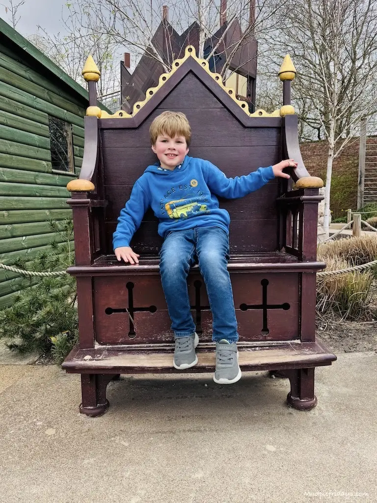 Harry sitting in one of the wooden thrones in the play area