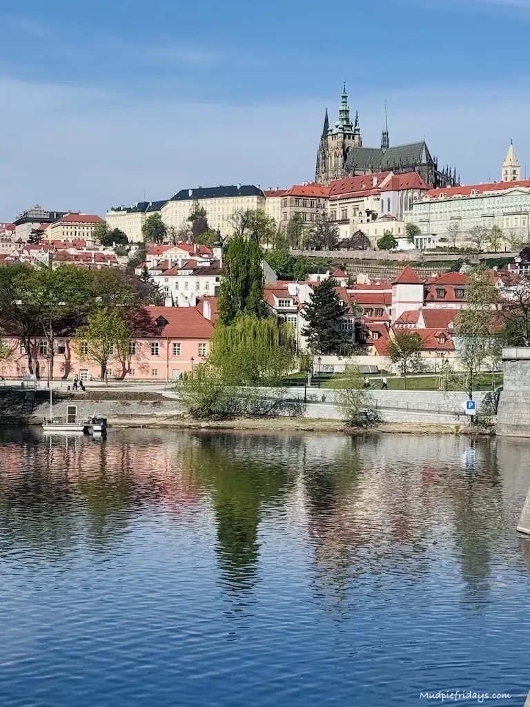 A view of Prague Castle from the other side of the river with reflections in the water on a sunny day