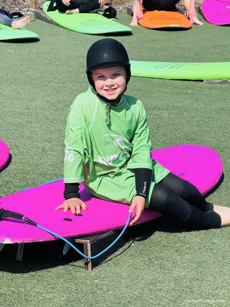 Harry sitting on his beginner's board at The Wave Bristol as part of the dry land lesson