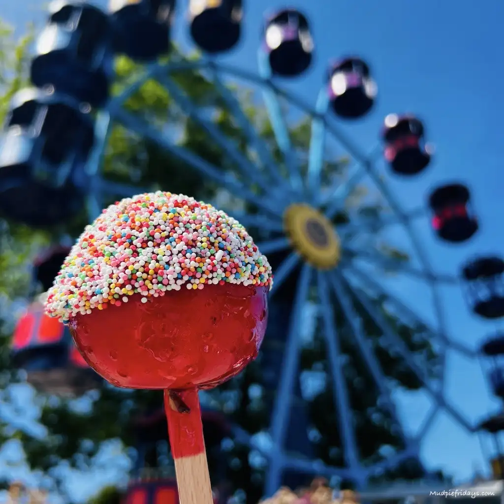 A candy apple in front of a fairground ride at Duinrell