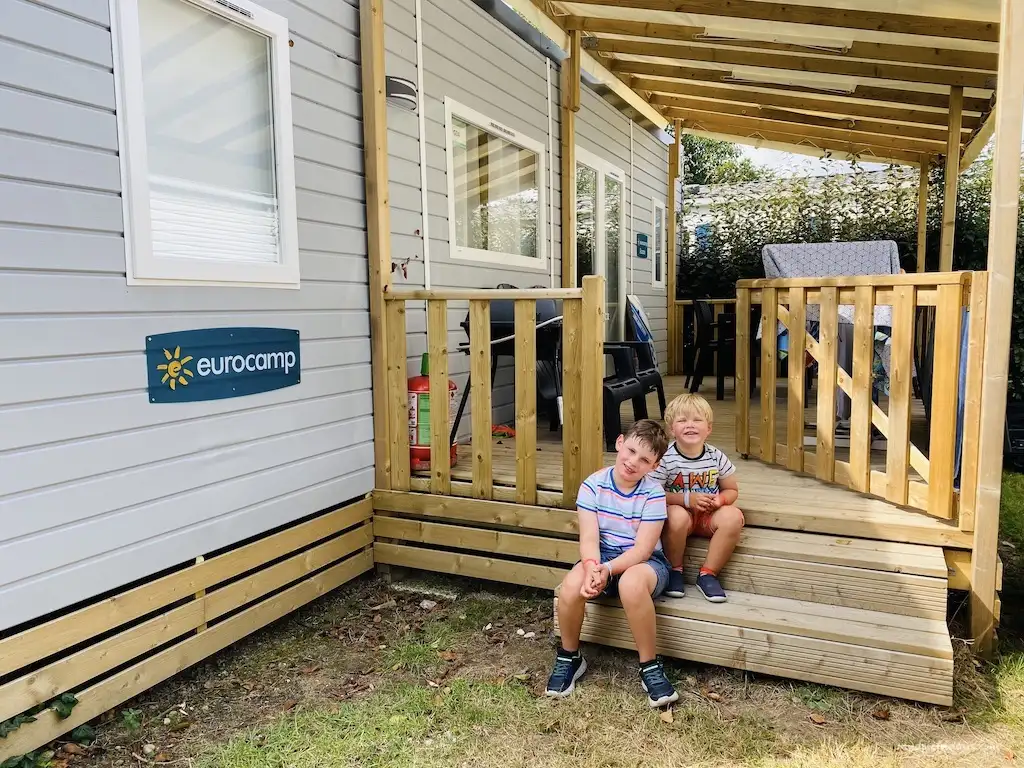 The boys sitting outside one of the mobile homes on the steps