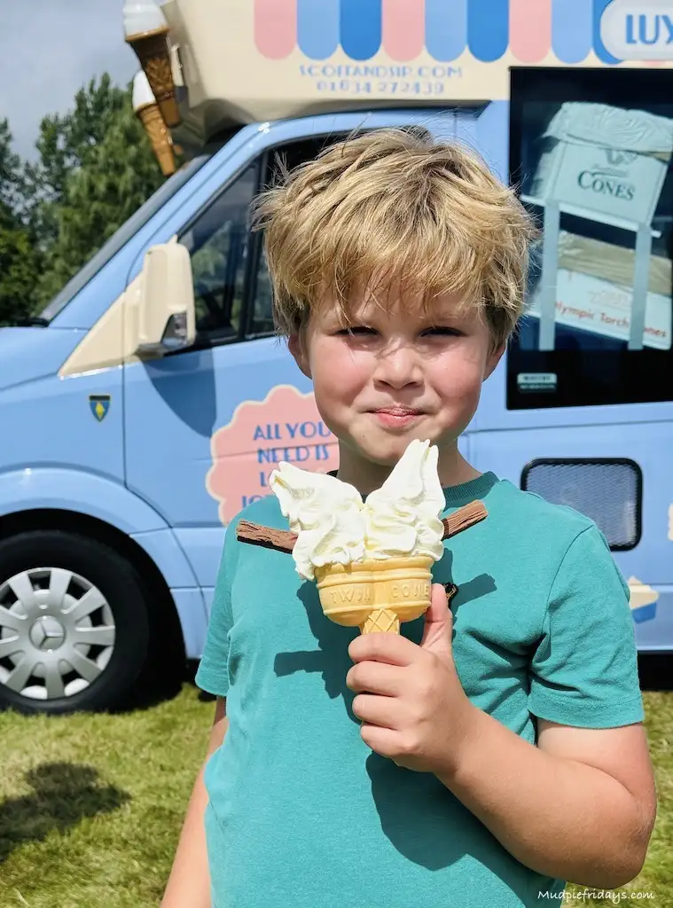 Harry eating a double whip ice cream with flakes with an ice cream van in the background