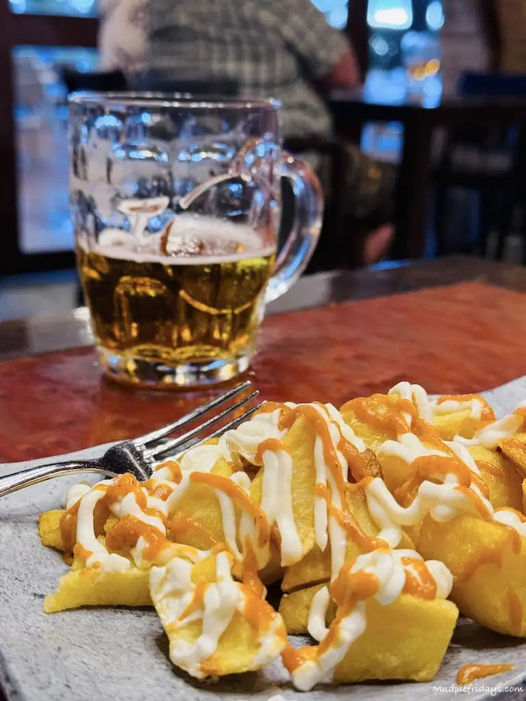 Patas Bravas and a beer in the background