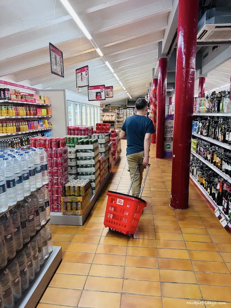 Charlie walking down the aisles pulling a basic at the campsite supermarket