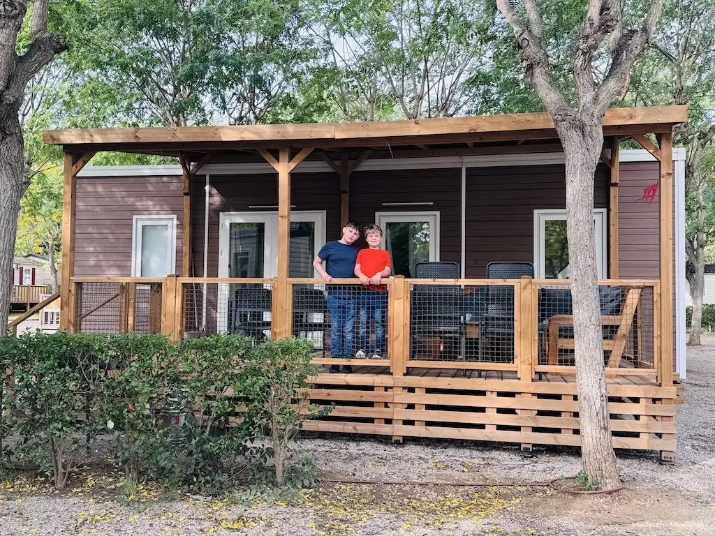 The boys standing on the decking of our premium mobile home staying at Vilanova Park with Eurocamp